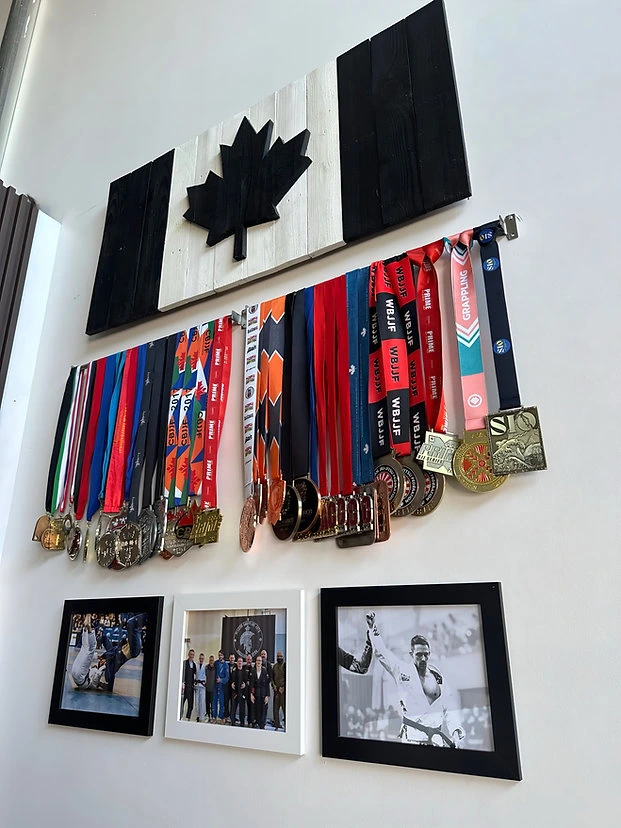 Competition medal wall and team photos inside Mission BJJ